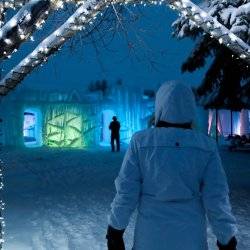 woman in snow clothing walking towards illuminated ice castle