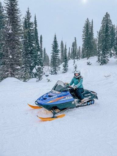 woman on snowmobile with snow in background