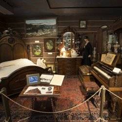 an exhibit of an old bedroom with antique, wooden furniture and a piano, at the Boundary County Historical Museum.