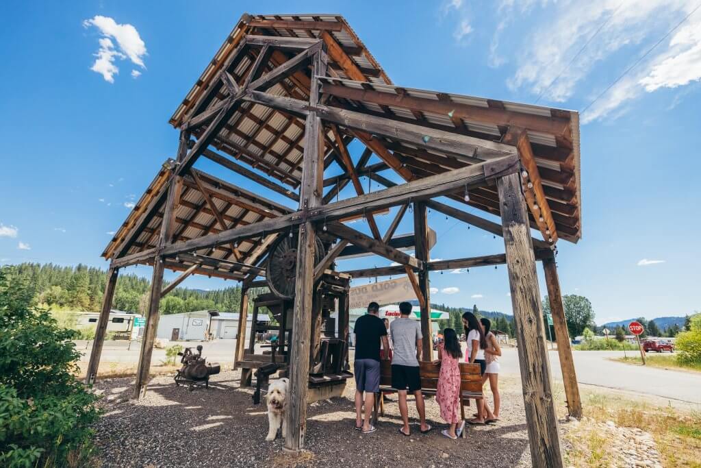 a group of people outside, at a mining equipment exhibit in Idaho City