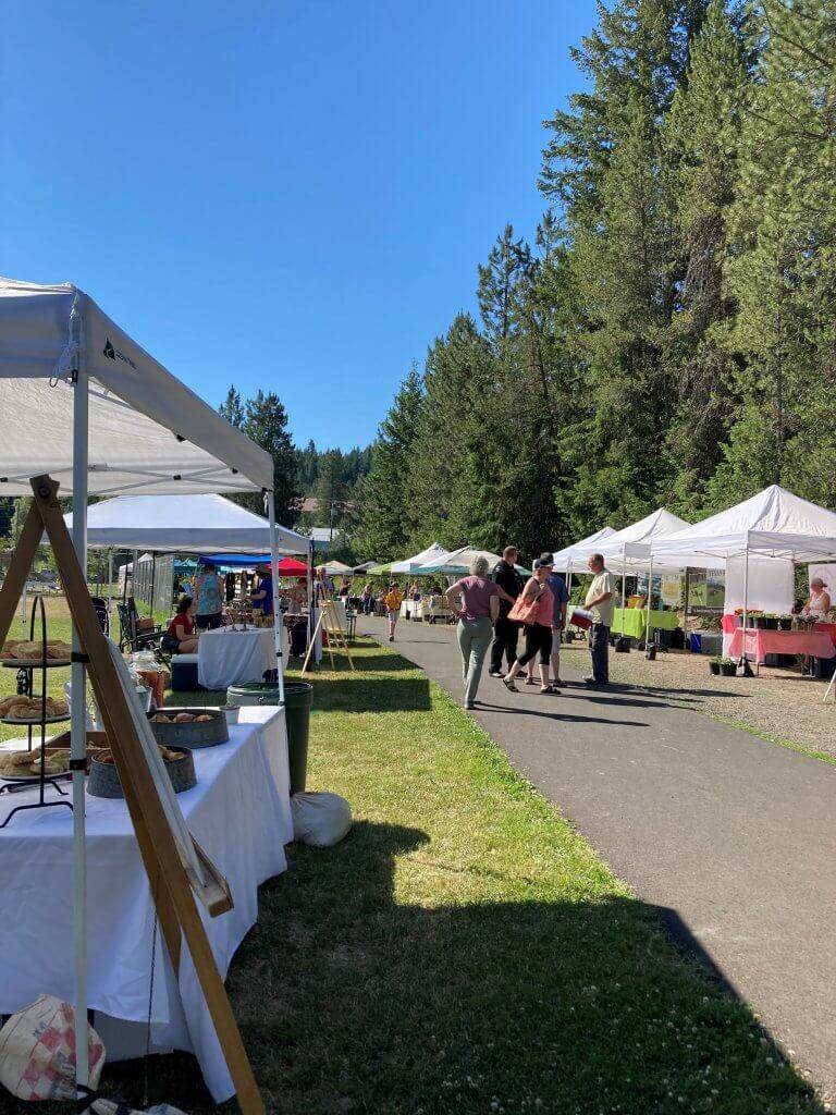 People walk and shop in the outdoor Latah Farmers Market.