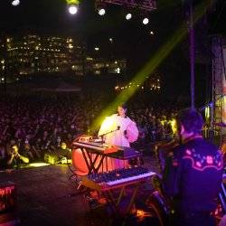 band on stage at night with large crowd in the background