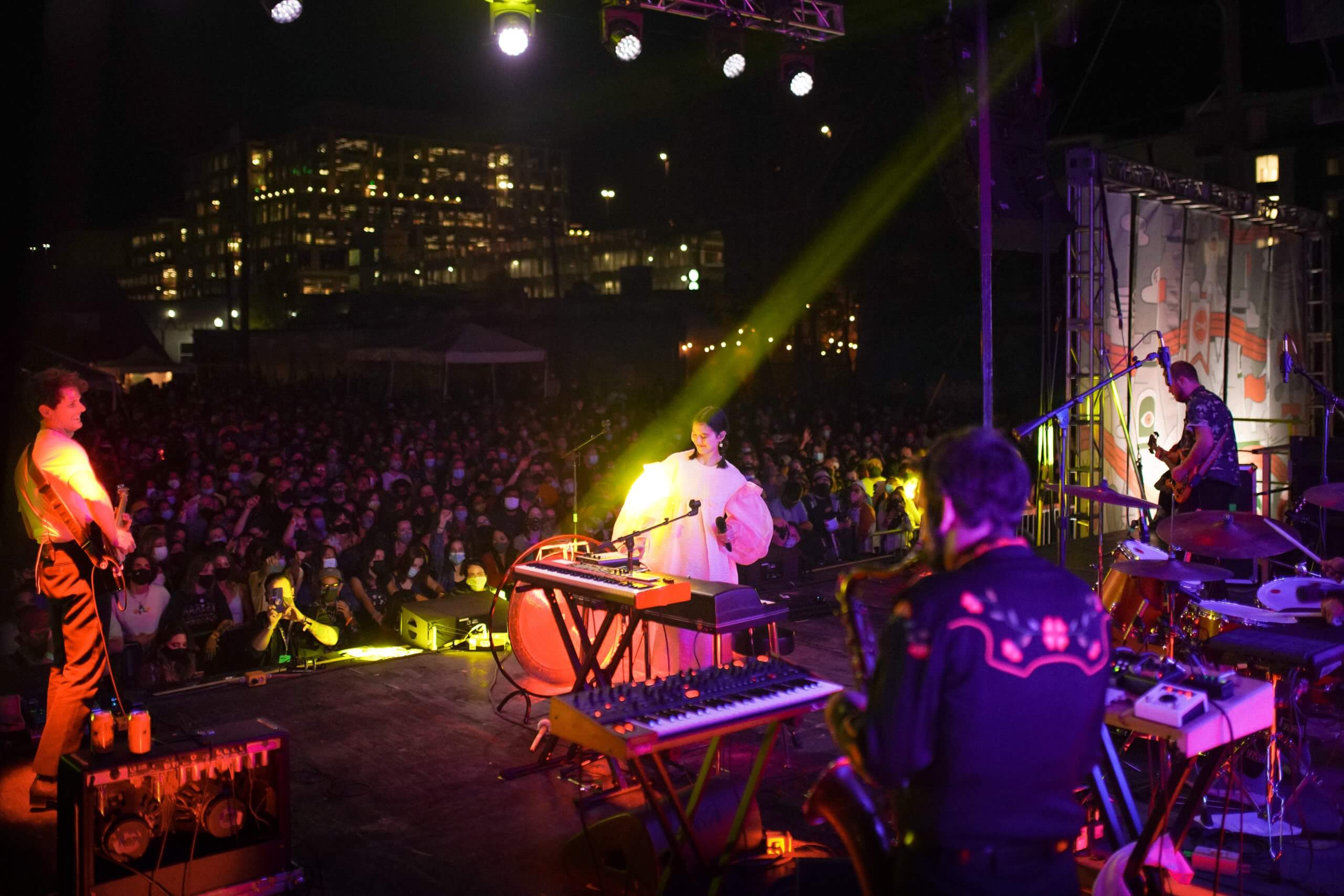 band on stage at night with large crowd in the background