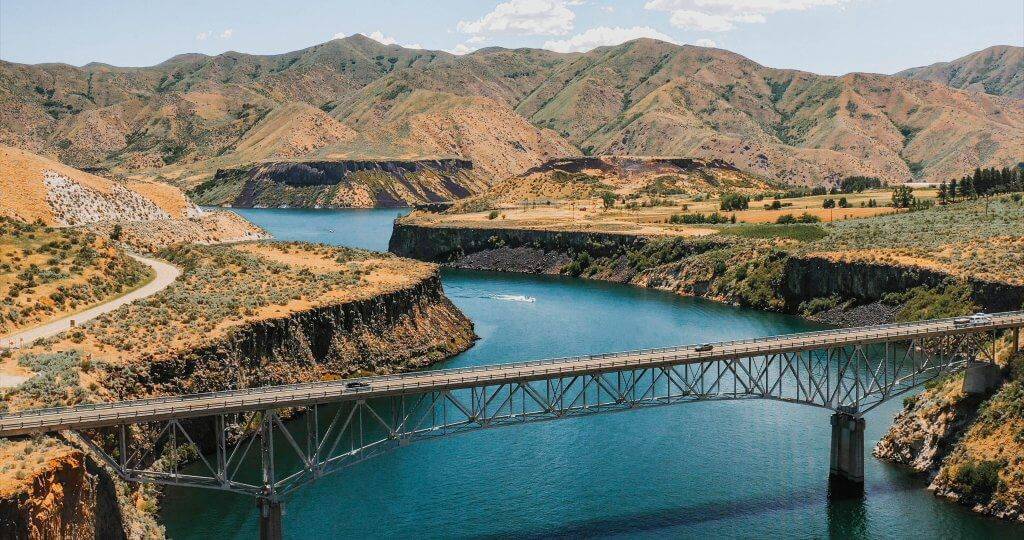 a bridge crossing a reservoir with mountains in the background