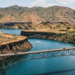 a bridge crossing a reservoir with mountains in the background