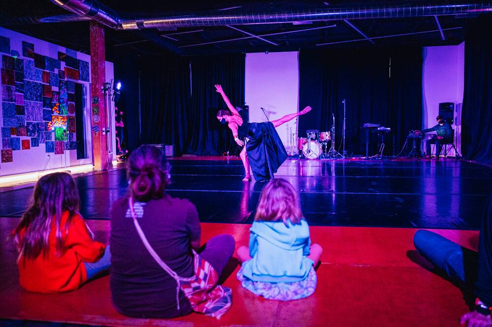 woman dancing with several people sitting on the floor watching the dancer