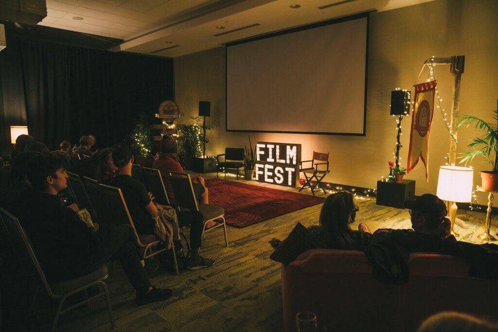 people sitting in front of large screen waiting for film to start