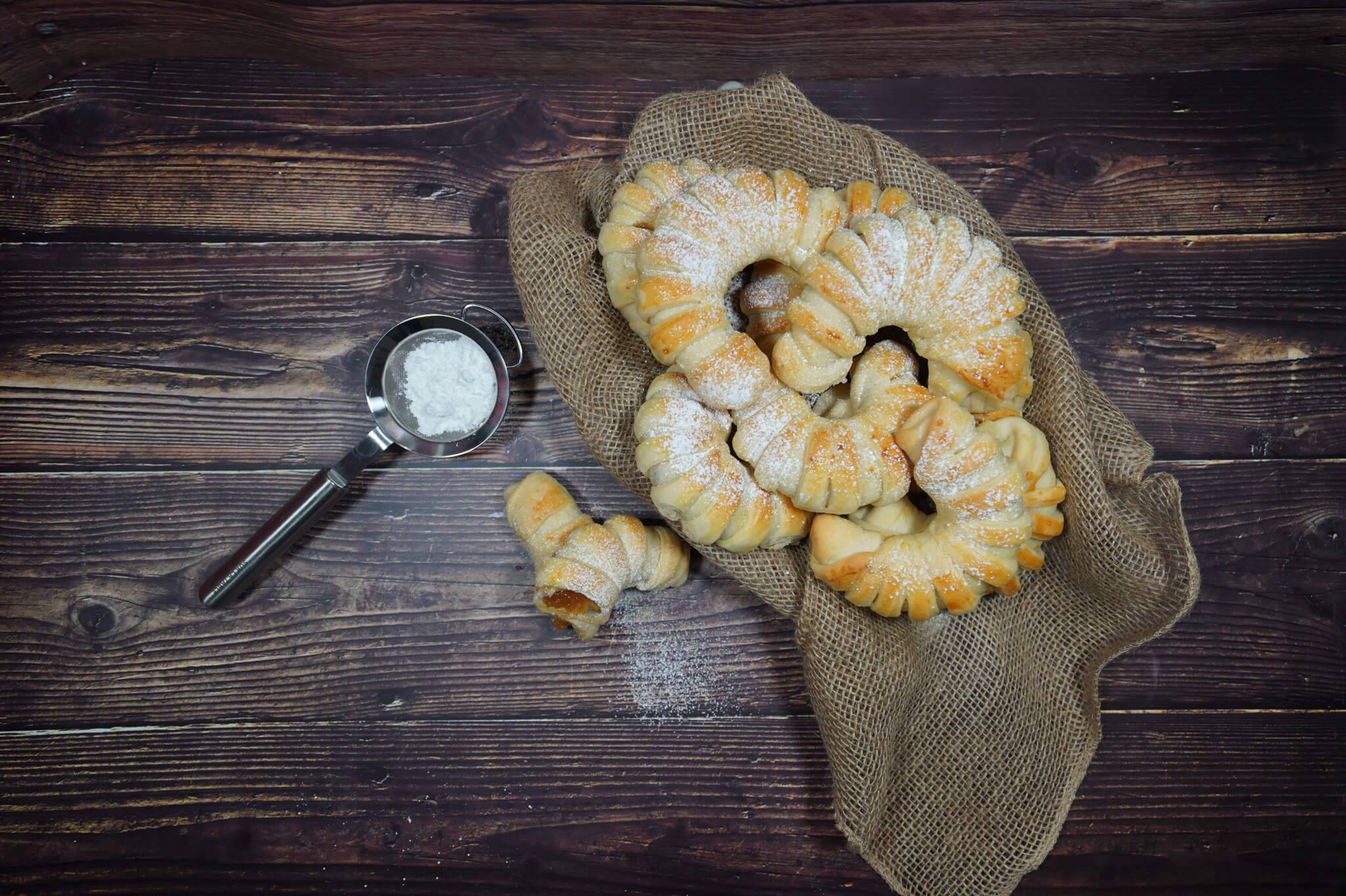 An overhead shot of rolls sprinkled with powder on a burlap cloth.