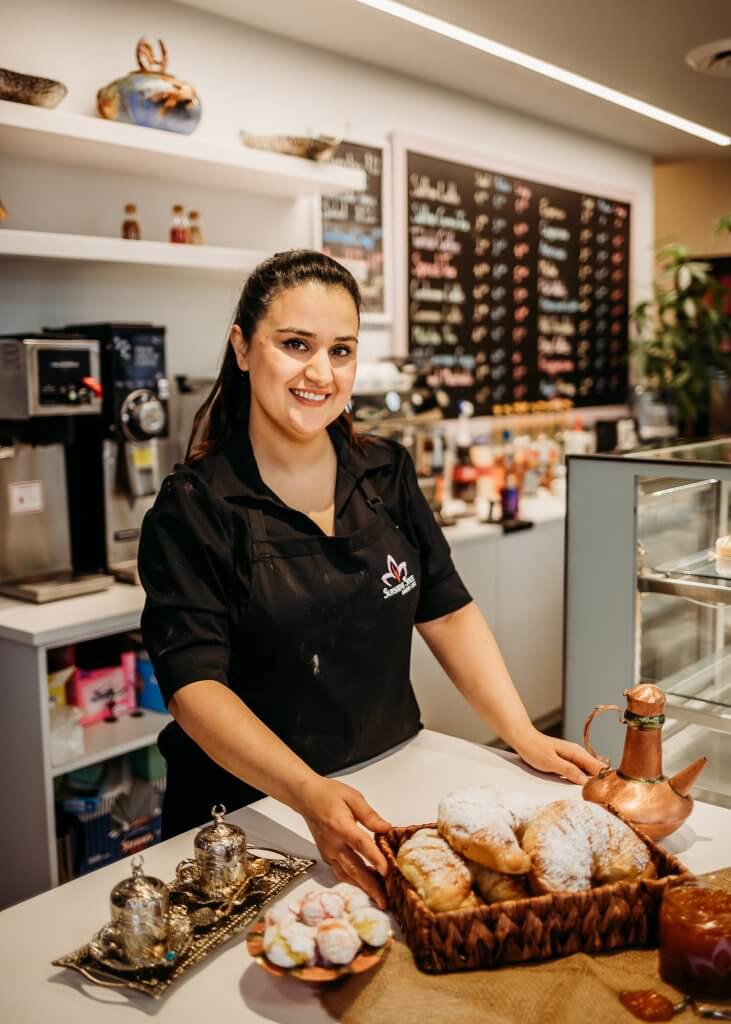 Sunshine Space Café chef Khatera Shams stands in front of a restaurant kitchen counter.