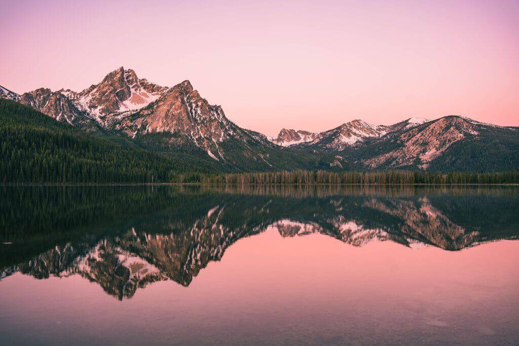 pink sky at sunrise reflecting over still Stanley lake