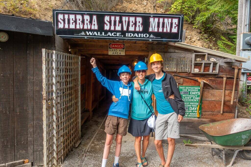 three people with hard hats on standing in front of sierra silver mine for tour