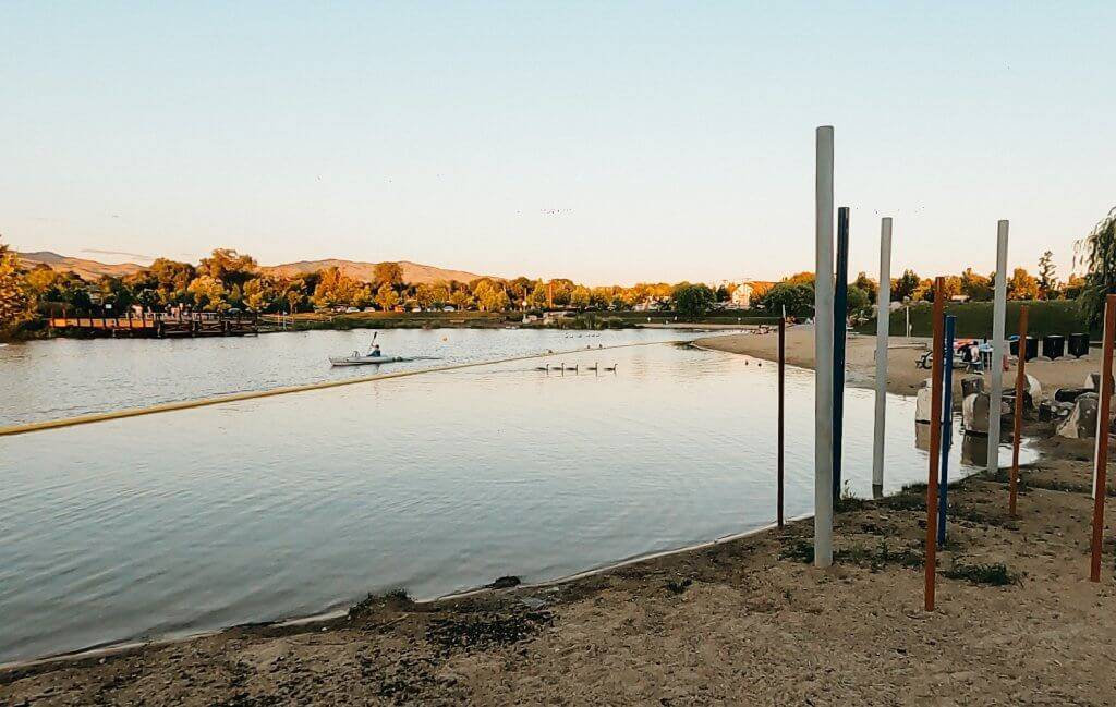 sandy beach with water and a kayaker off in the distance