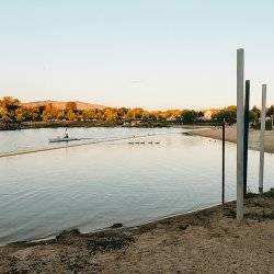 A sandy beach and a person kayaking in the distance at Esther Simplot Park.