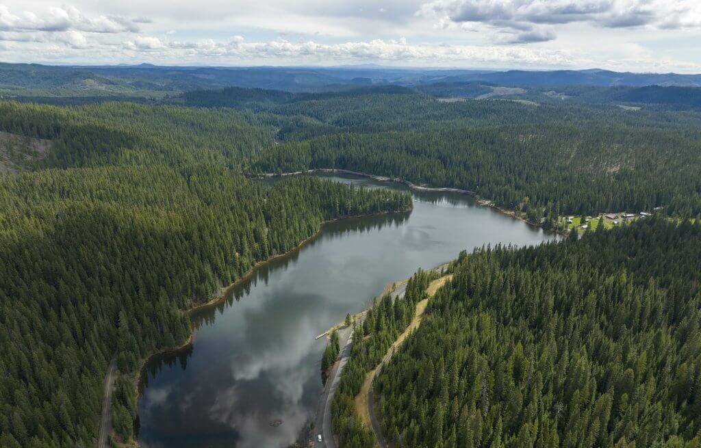 A scenic look at the river mirroring clouds along the Dworkshak Reservoir lined on each side with trees.