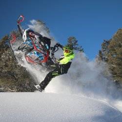 A snowmobiler launches off a jump on a winter trail in Bear Lake Valley.