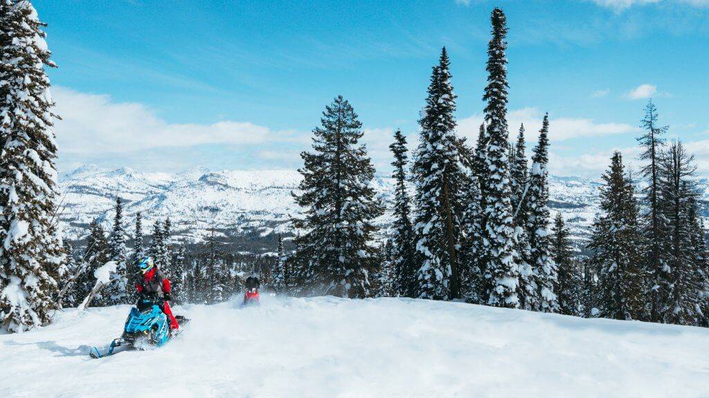 Two snowmobilers on a winter trail at Brundage Mountain Resort.