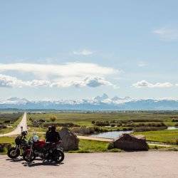 Two people overlooking the Teton Mountains on their motorcycles.