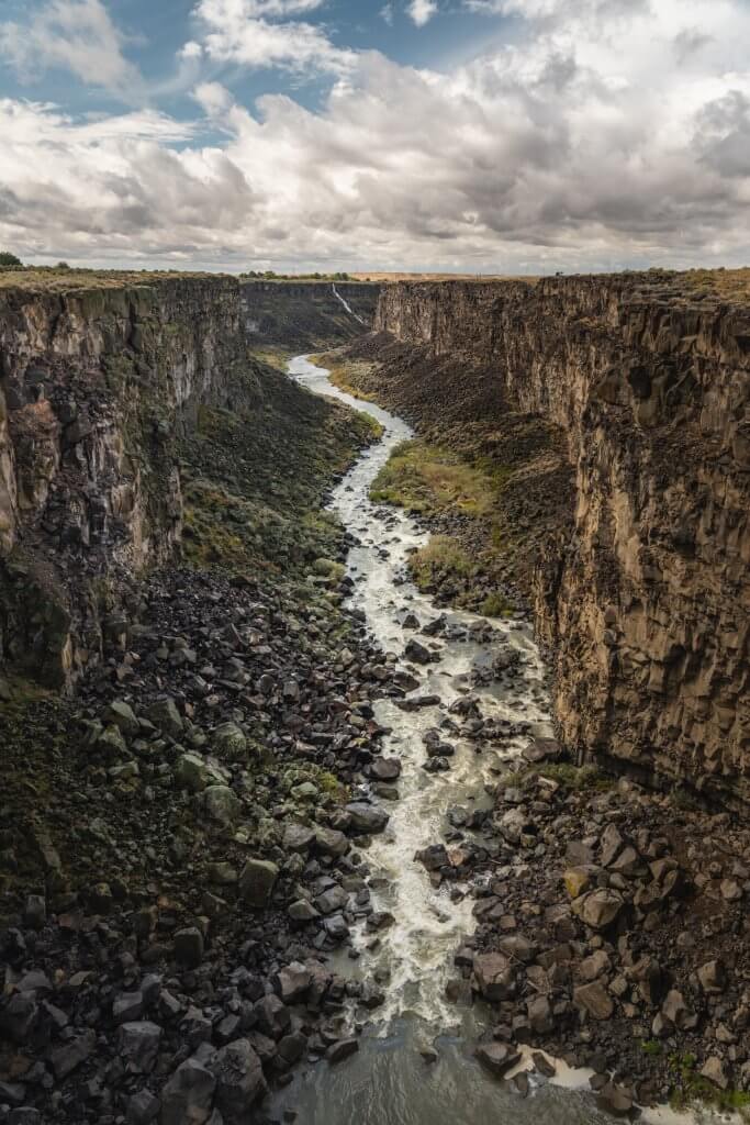 deep and rugged river canyon with small river flowing in around rocks in the bottom of malad gorge