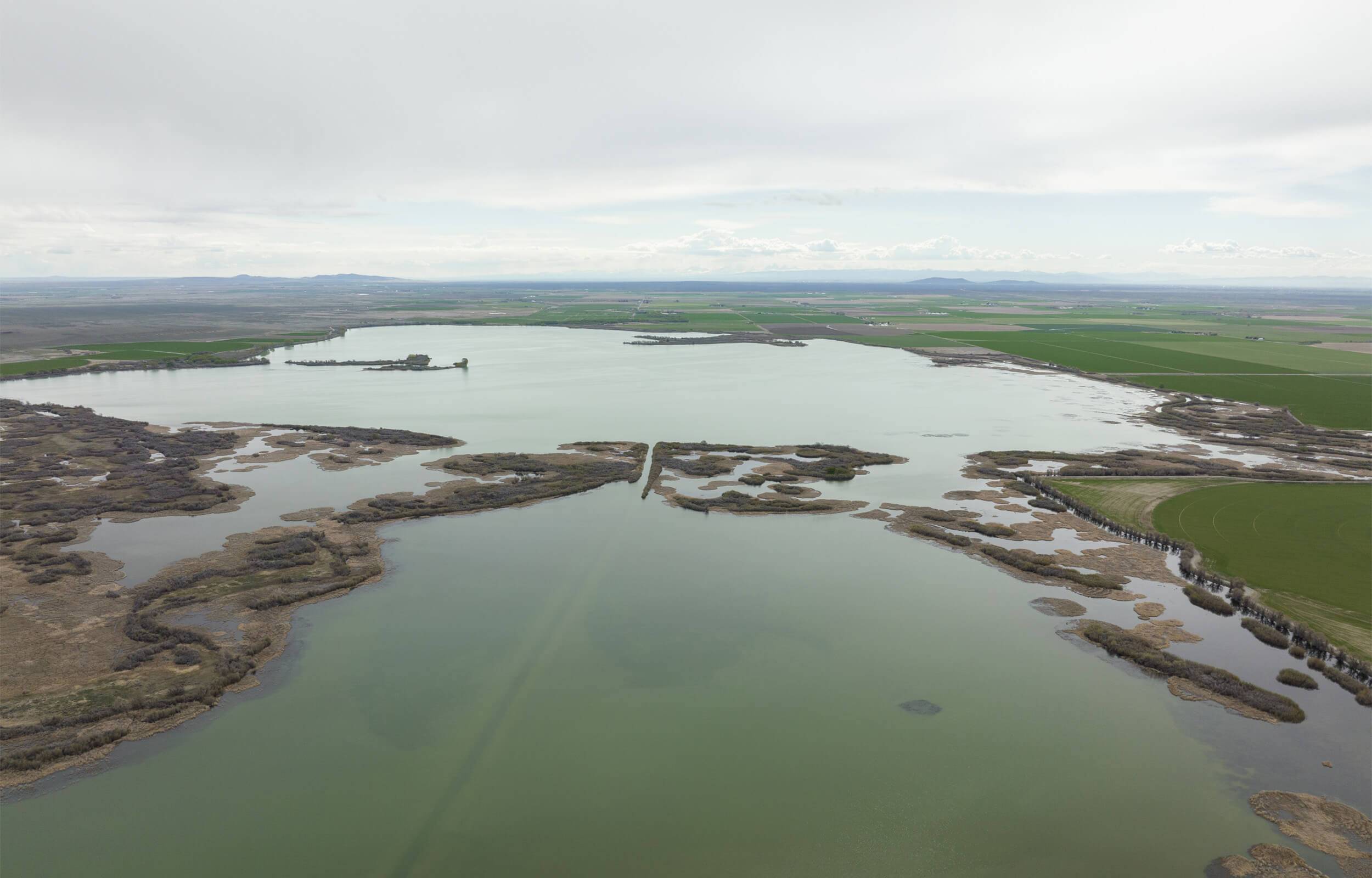 Aerial view of Mud Lake, with green landscapes in the distance.