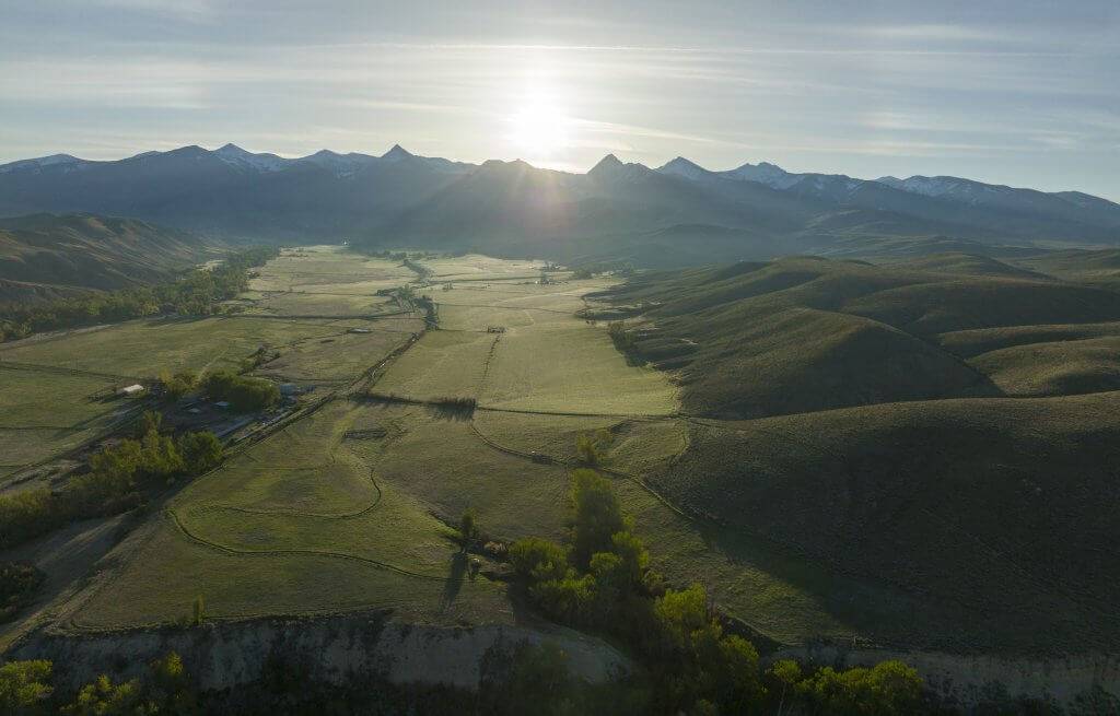 Sprawling view of a green landscape with the Beaverhead Mountains in the distance.