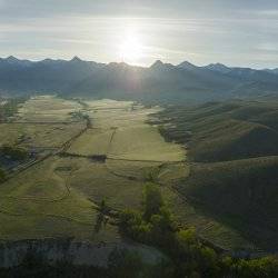 Sprawling view of a green landscape with the Beaverhead Mountains in the distance.