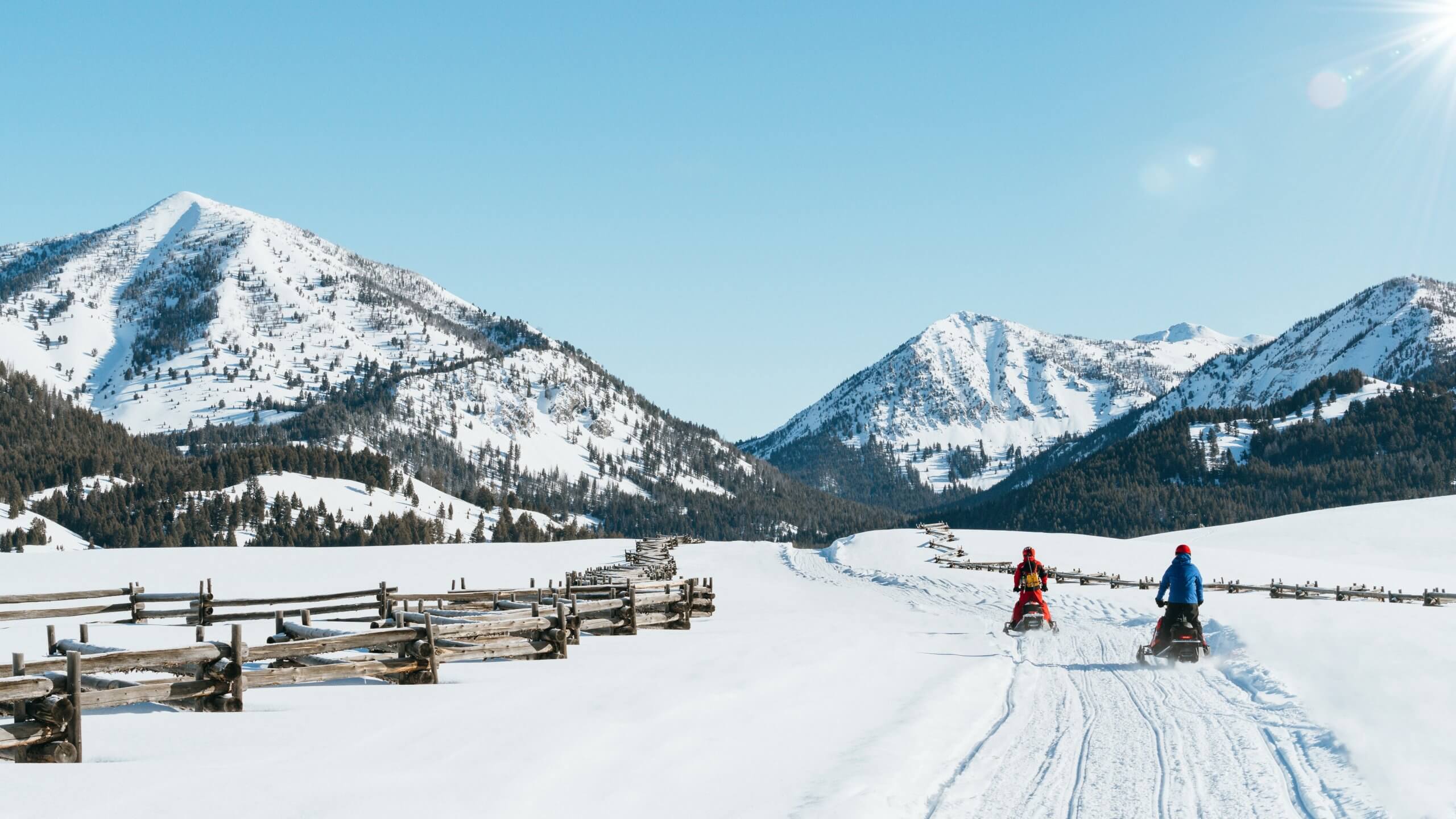 Two snowmobilers on a winter trail at Smiley Creek Lodge.