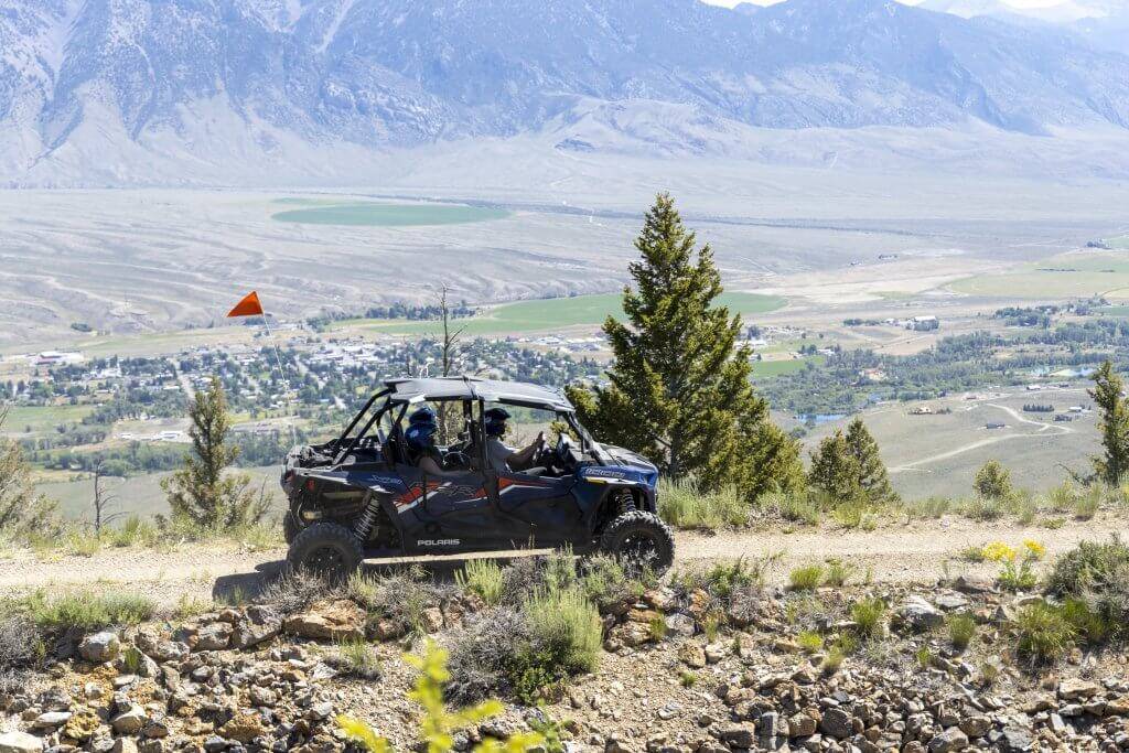 A group of people rides in an OHV riding above the city of Mackay in the background. 