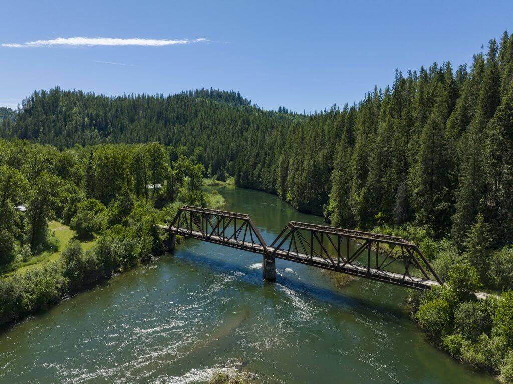 A view of the St. Joe River flowing beneath the bridge, lined with trees.