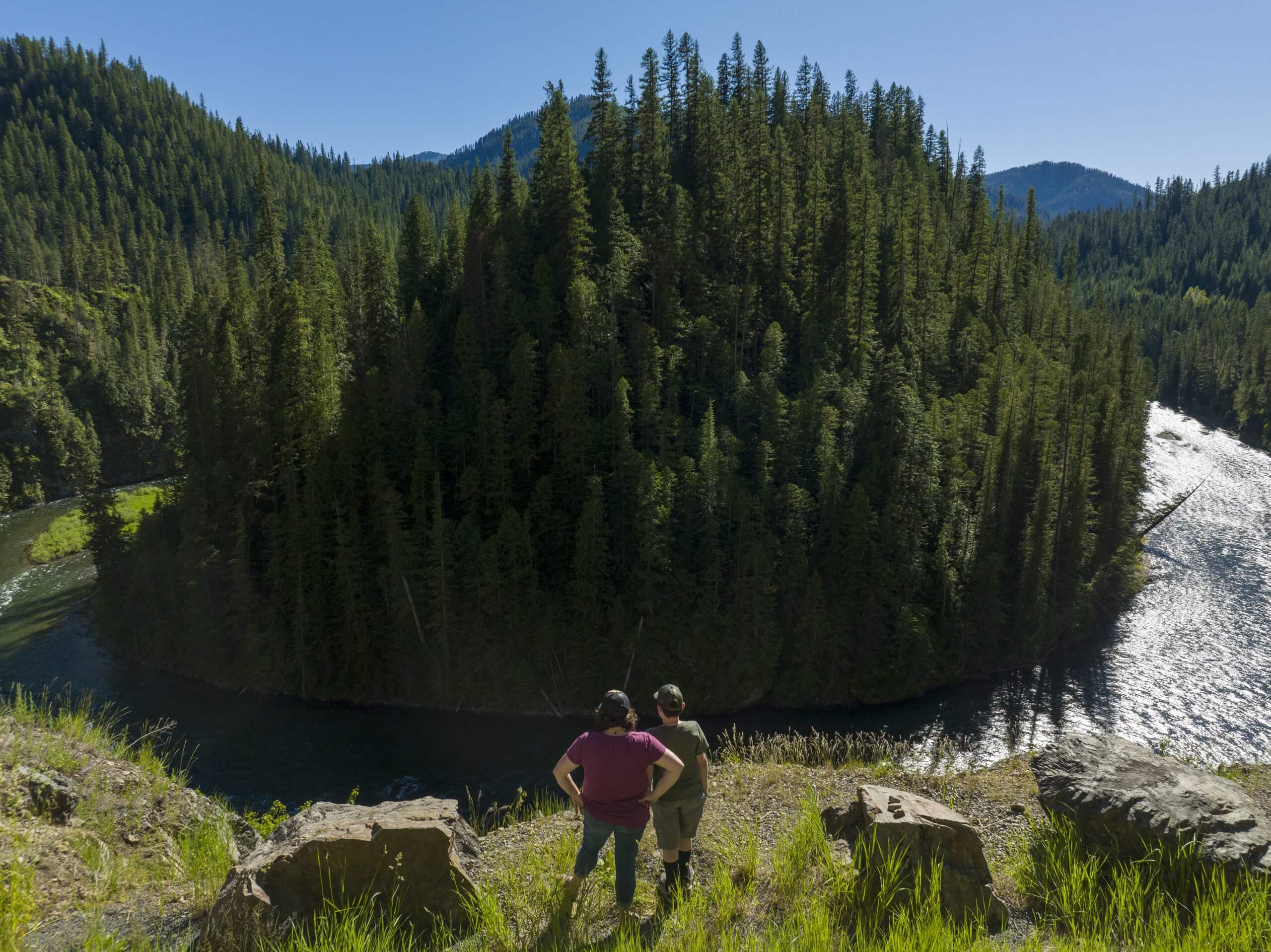 Two people stand on a ridge overlooking Saint Joe River.