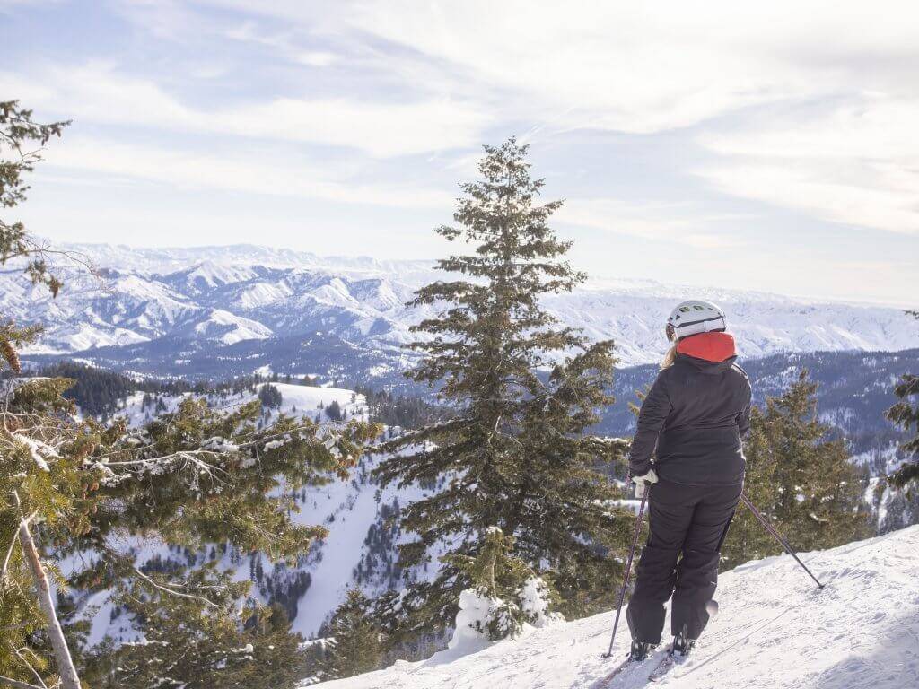 one skier at Bogus Basin standing on snowy mountain looking at snowy views in the distance