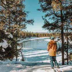 A person on snowshoes standing in front of water at Harriman State Park.