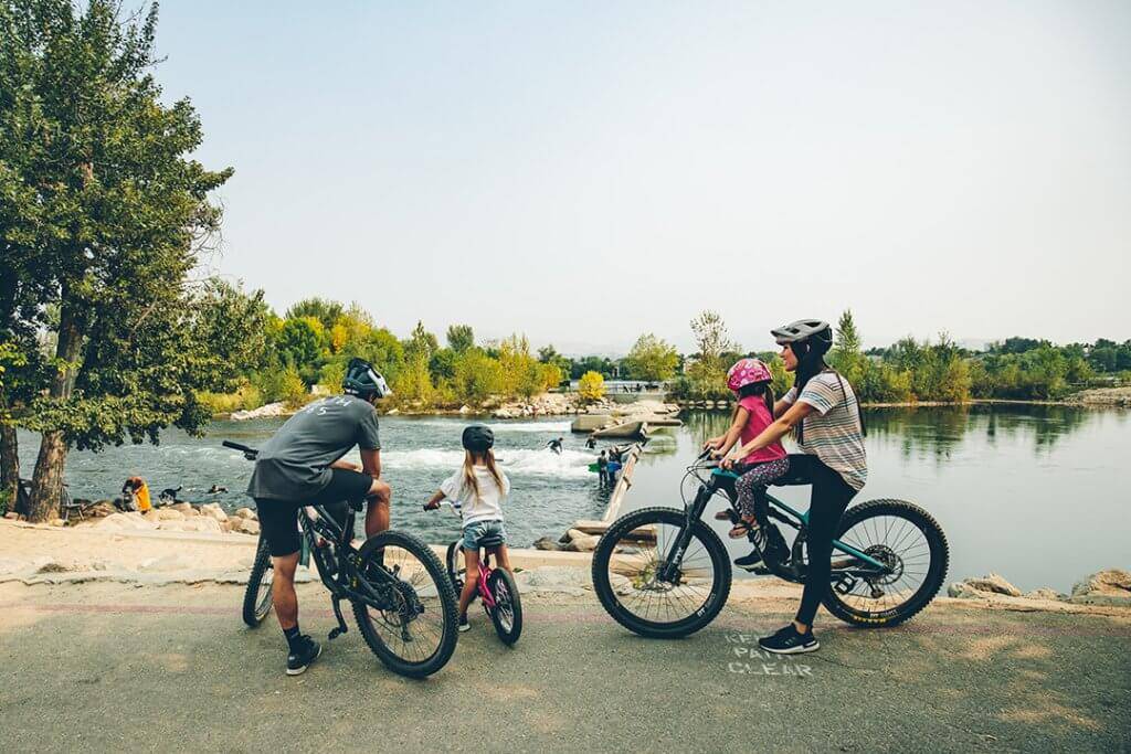 Four people with bikes stop along the Boise River Greenbelt.