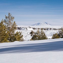 A view of the snow-covered landscapes and a cinder cone in the distance at Craters of the Moon National Monument & Preserve.