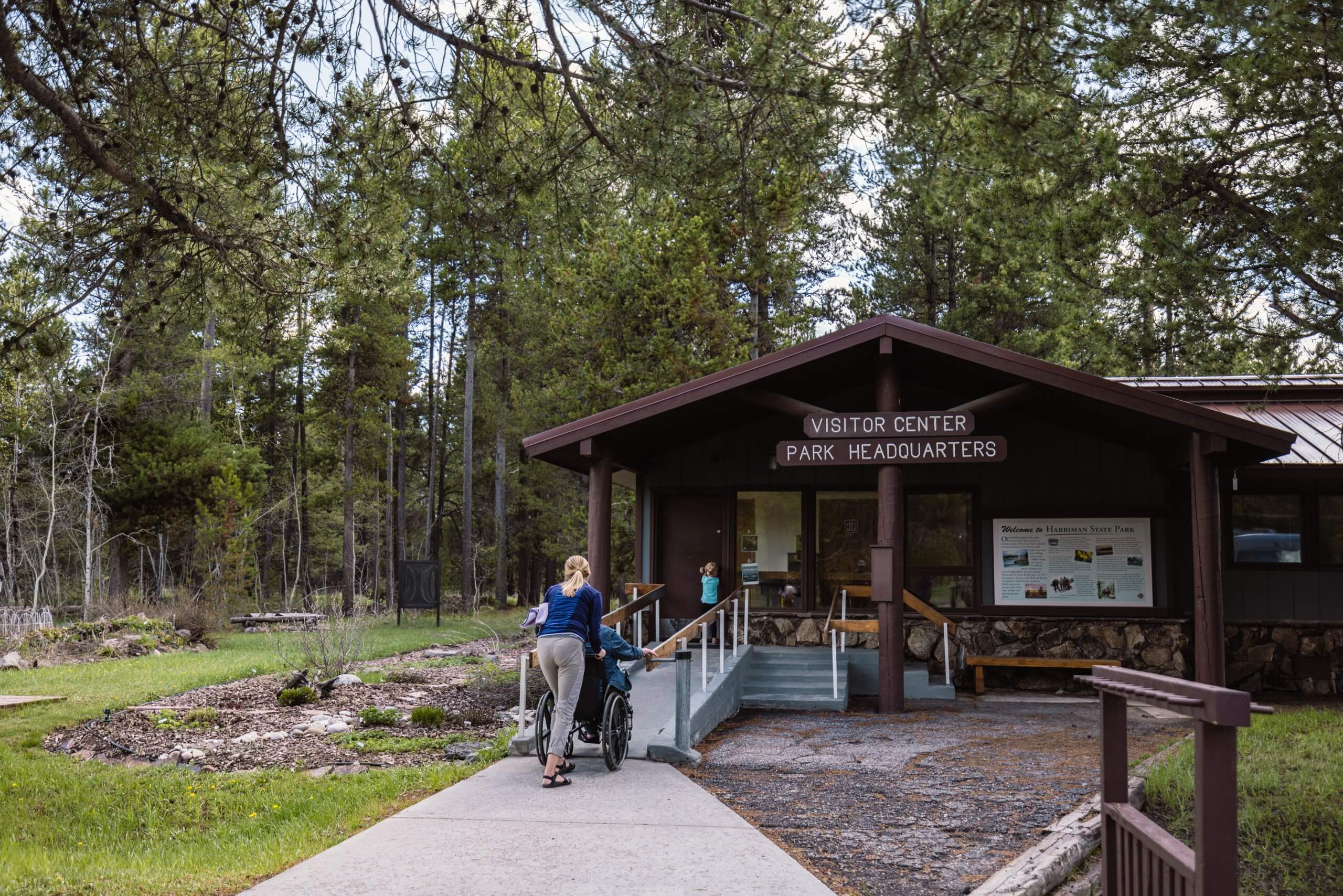 A woman pushes a person in a wheelchair up the ramp at the Harriman State Park Visitor Center.