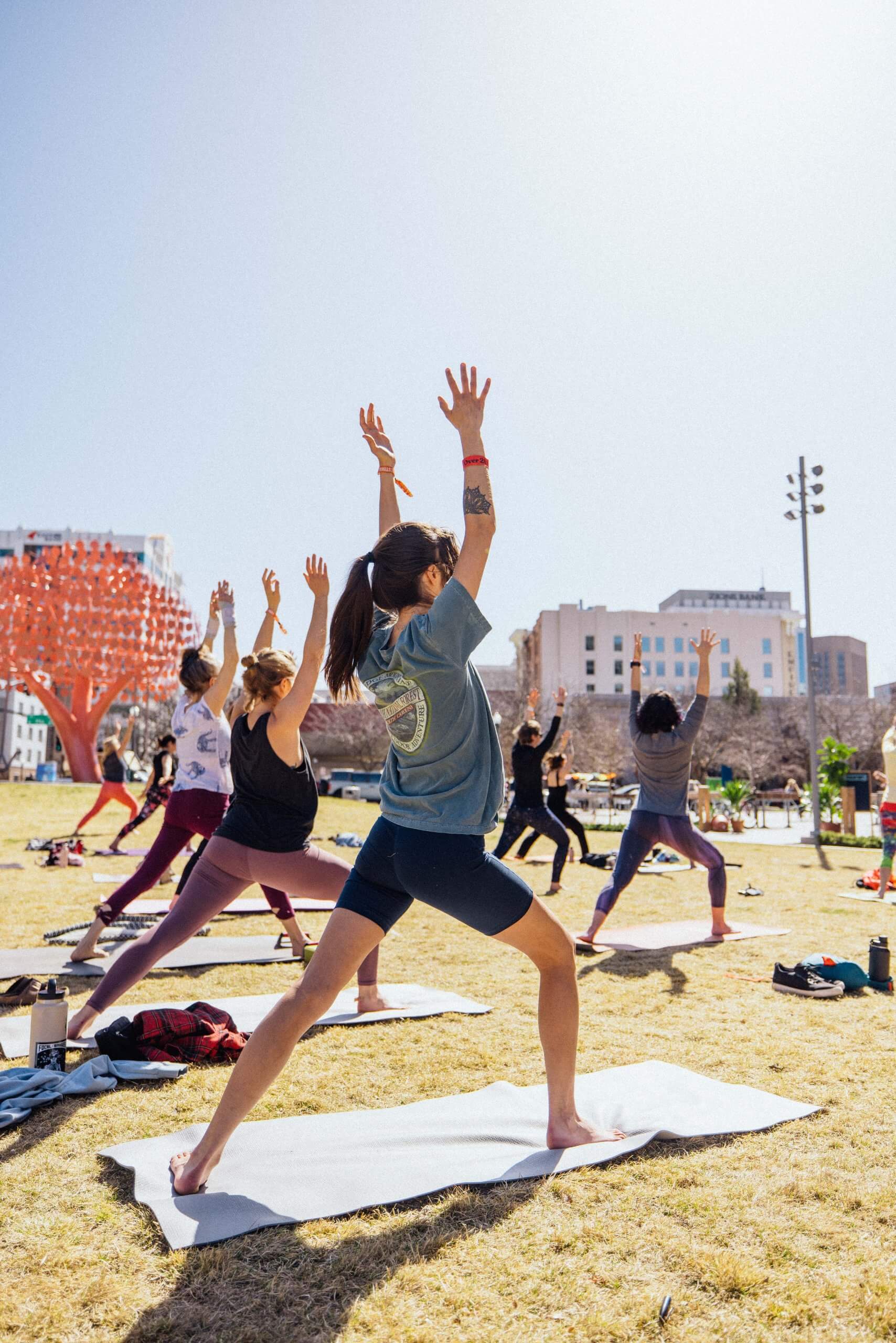 Five people in athletic attire stand on yoga mats in the grass at Yogafort in downtown Boise.