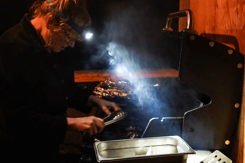 woman with headline on uses the light to look at food she is grilling 