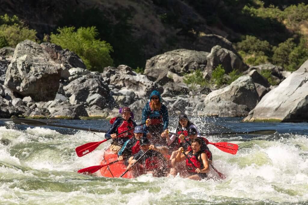 A whitewater raft with seven people drops into a splashy rapid on the Snake River in Hells Canyon.