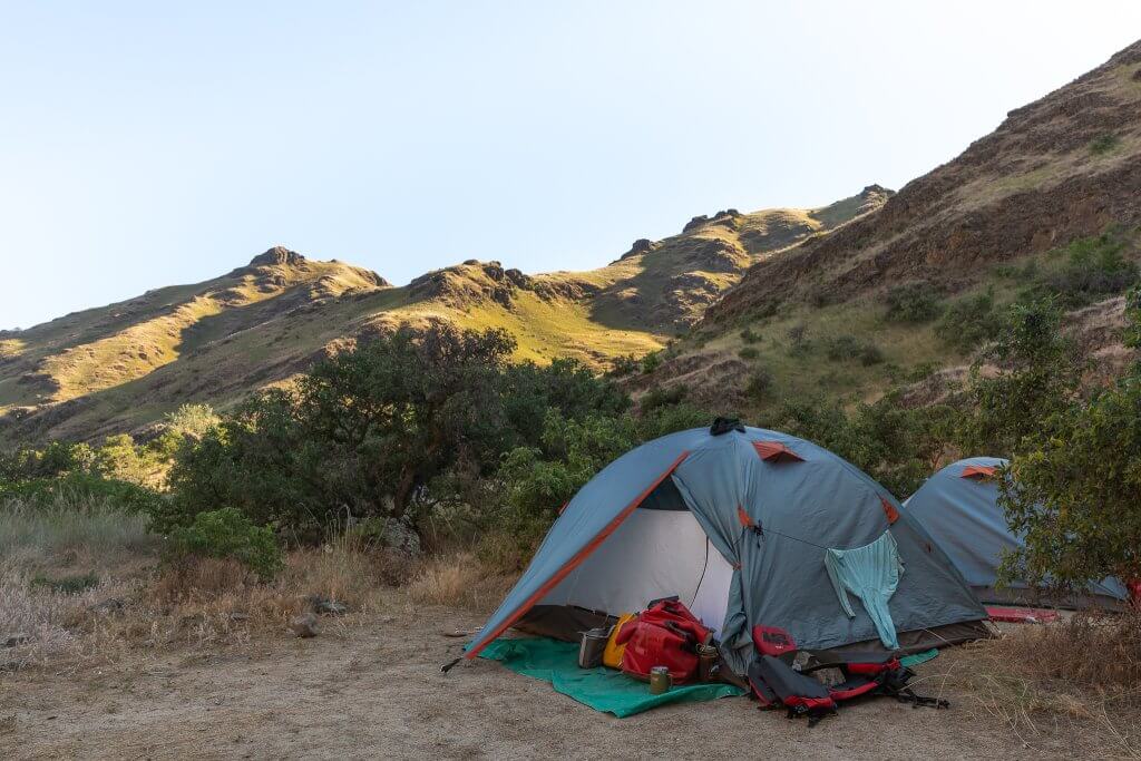 A small tent setup on a sandy beach in Hells Canyon.