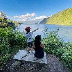 a mother and son sit on a bench overlooking the scenic Lake Pend Oreille at Farragut State Park.