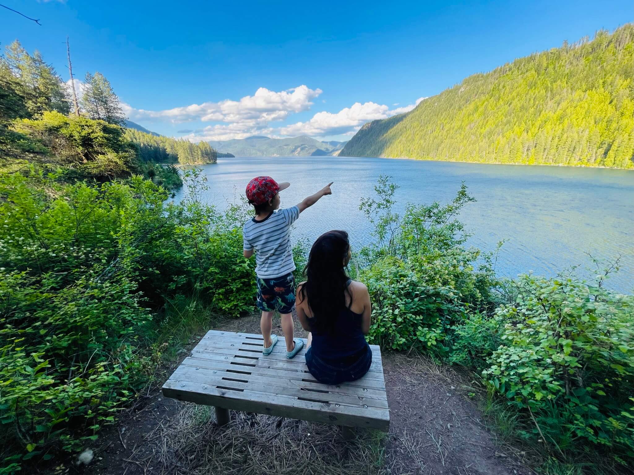 a mother and son sit on a bench overlooking the scenic Lake Pend Oreille at Farragut State Park.