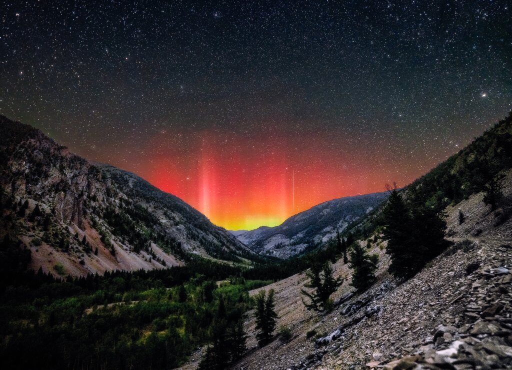 Red and yellow northern lights over the mountains at Trail Creek Pass near Sun Valley.