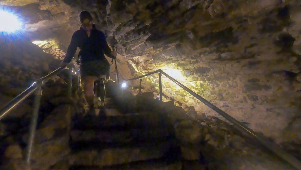 A woman with a prosthetic leg walks down stone steps inside Minnetonka Cave.