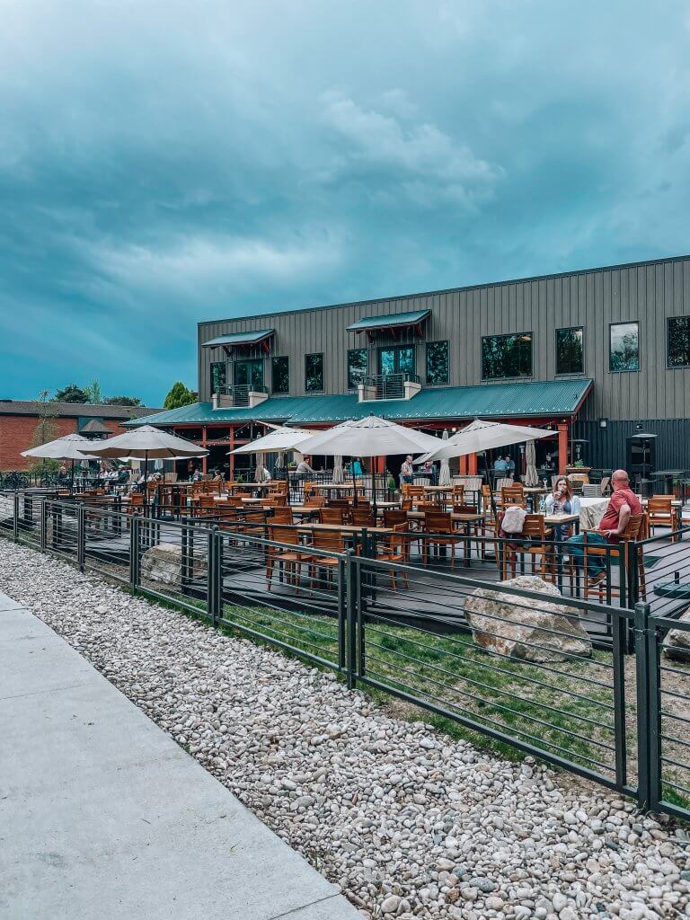 Exterior patio of Telaya Winery with five large umbrellas providing shade to several tables and multiple guests.