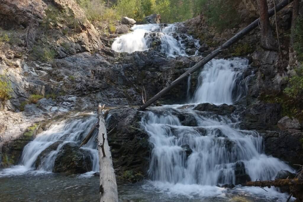 Water runs down three different rock faces creating a multi-tiered waterfall.