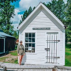 A woman stands outside a white historic building in Idaho City.