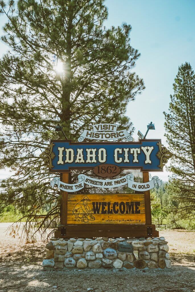 A large, wood roadside sign welcomes visitors to Idaho City.