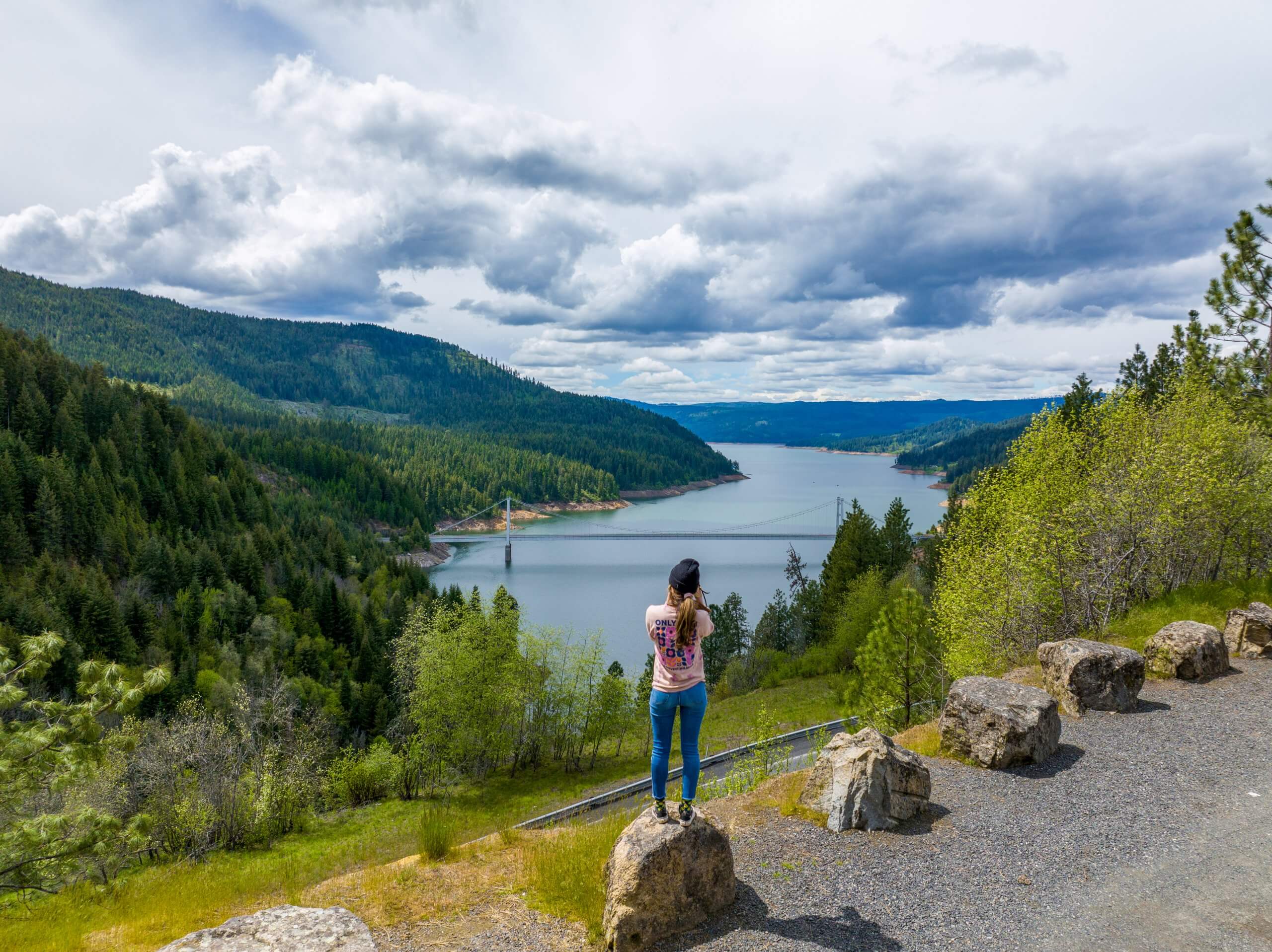 A woman stands on a rock overlooking the Dent Bridge.