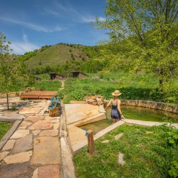 A woman and child approach a developed hot spring pool from a landscaped path.