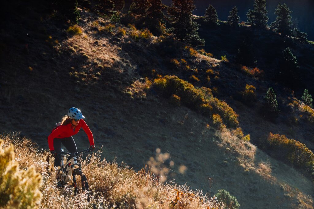 A female mountain biker riding a dirt trail in the Boise Foothills surrounding by sagebrush.