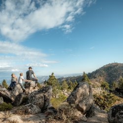 A family sits on a variety of boulders overlooking the valley at Mores Mountain.